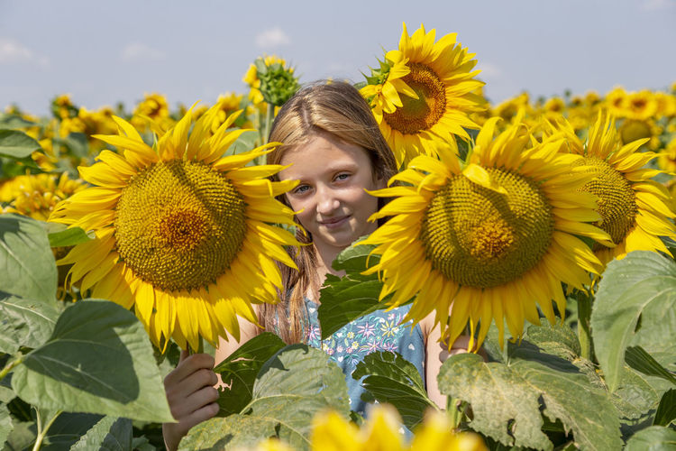 Girl with the smile surrounded with bright blooming sunflowers. generation z.