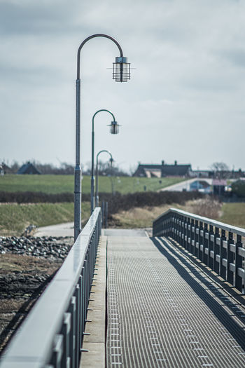 Railroad tracks by street against sky