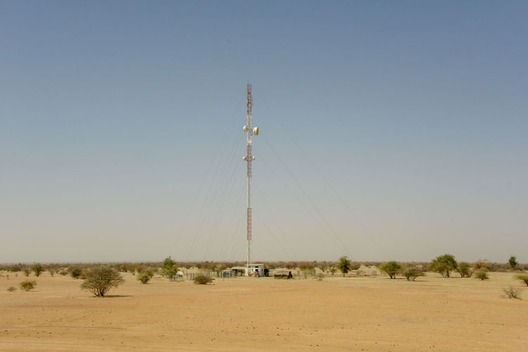 Communications tower on field against clear sky