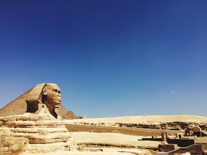 The great sphinx and pyramids against clear blue sky