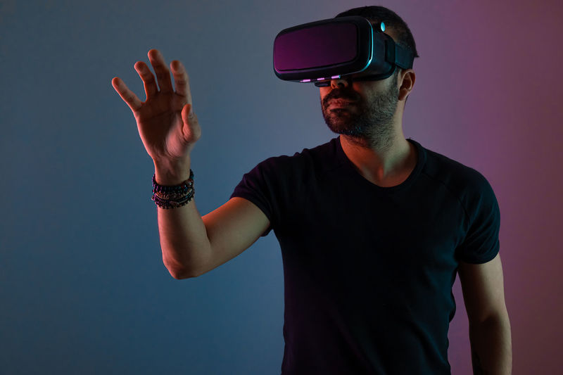 Young man in vr glasses headset interact with virtual reality in color neon light,  video gaming