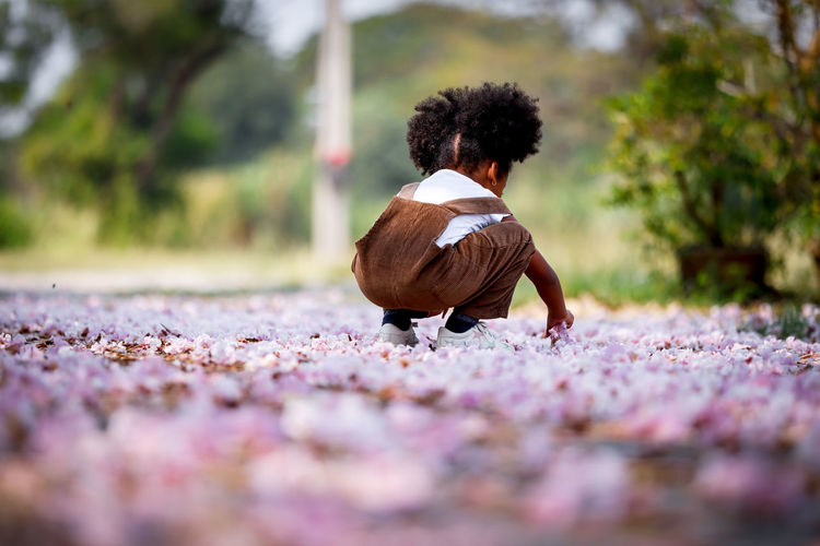 Rear view of girl crouching on land