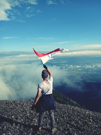 Rear view of man standing on sea against sky