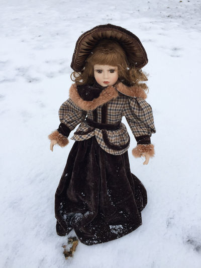 Portrait of young porcelain doll standing in snow
