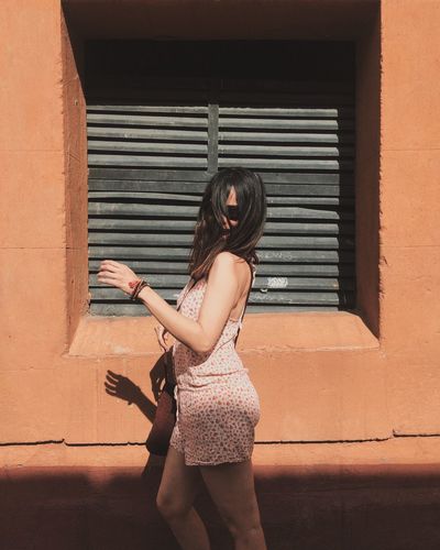 Woman with hands standing against brick wall