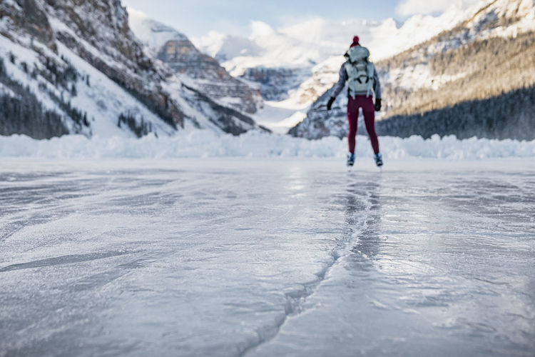 Young woman skating on frozen lake louise in banff towards mountains
