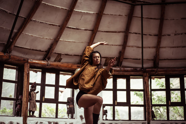 Mixed race fashionable dancer dances in stone and straw dome studio