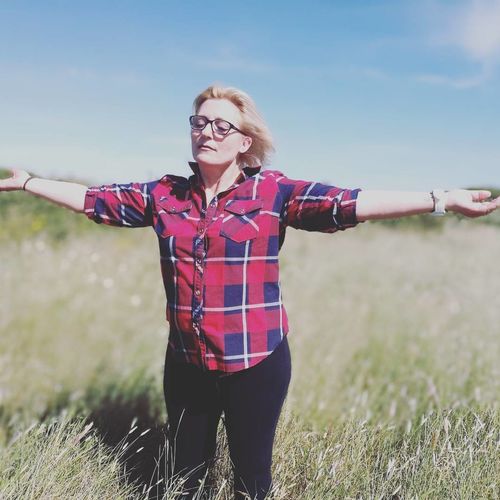 Woman with arms outstretched standing on grassy field