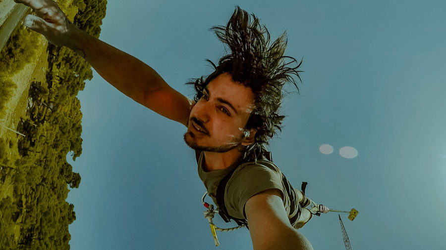 Low angle view of man hanging against clear sky