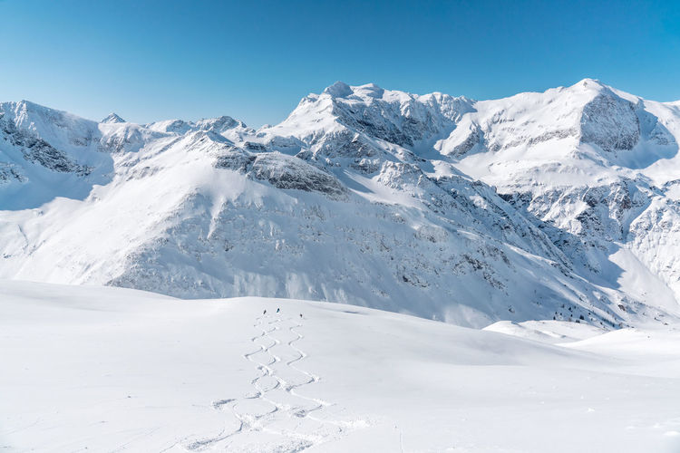 Group of people skiing in fresh powder snow in vast alpine landscape, gastein, austria.