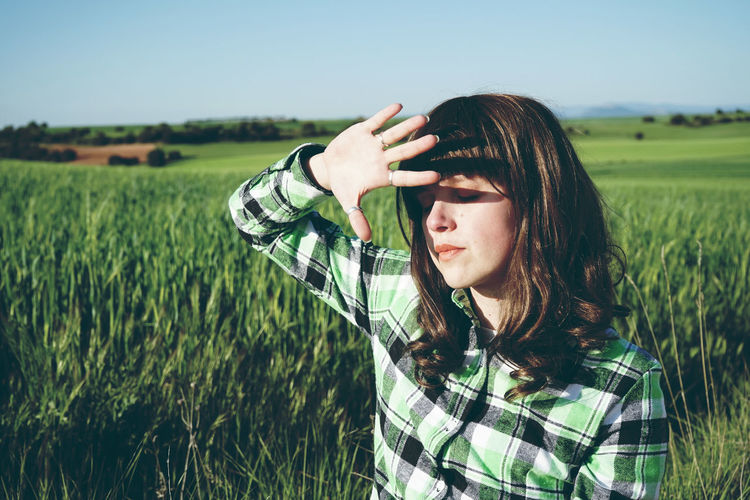 Woman with eyes closed standing on field during sunny day