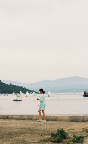 Side view of woman standing by lakeshore