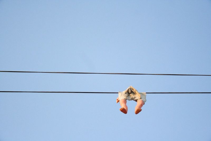 Low angle view of toy hanging from cable against clear sky