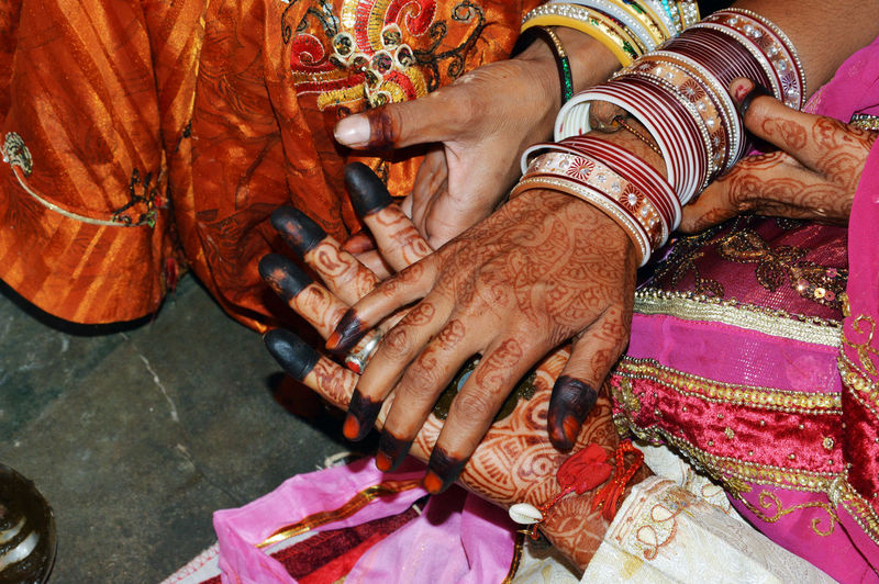 Bride and groom with henna painted hands completes hand matching ceremony in indian traditions.
