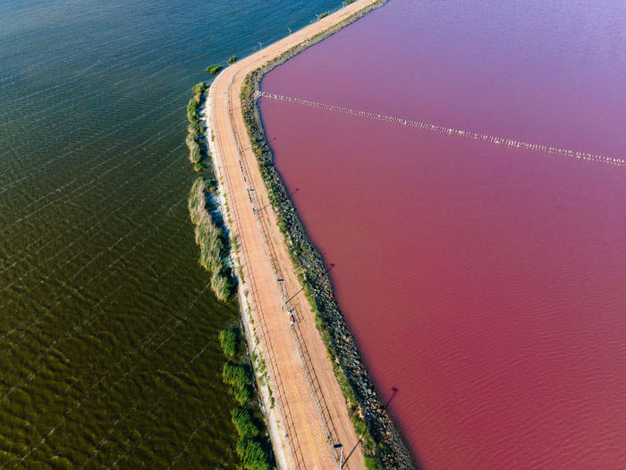Road that separates the pink salt lake and the black sea view from the drone