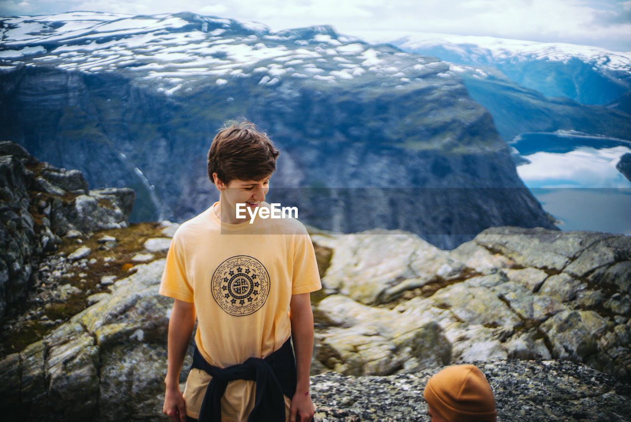 High angle view of young man smiling while standing at trolltunga during winter