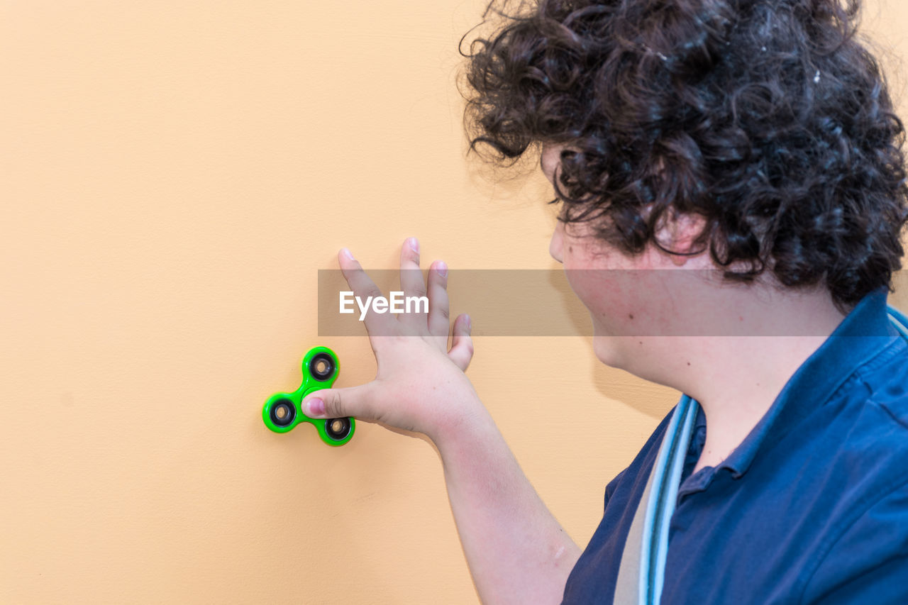 Boy playing with fidget spinner on wall