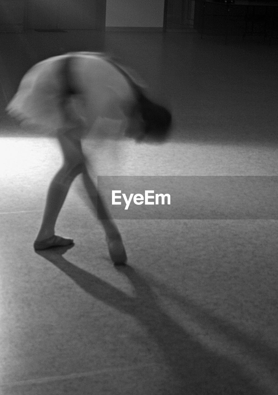 Blurred motion of ballet dancer dancing in studio 