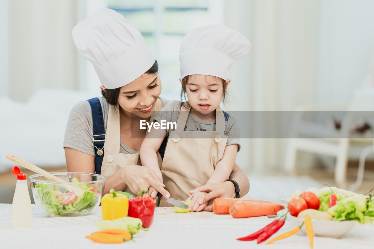 MIDSECTION OF WOMAN AND VEGETABLES AT HOME