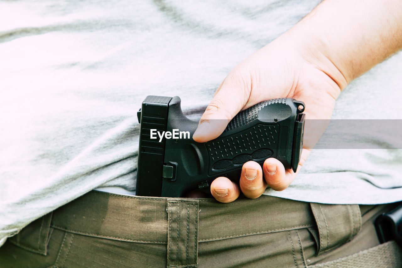 Midsection of man holding handgun