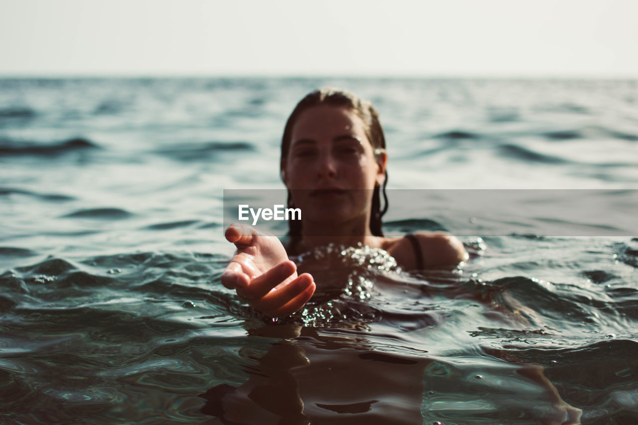 Portrait of woman gesturing while swimming in sea