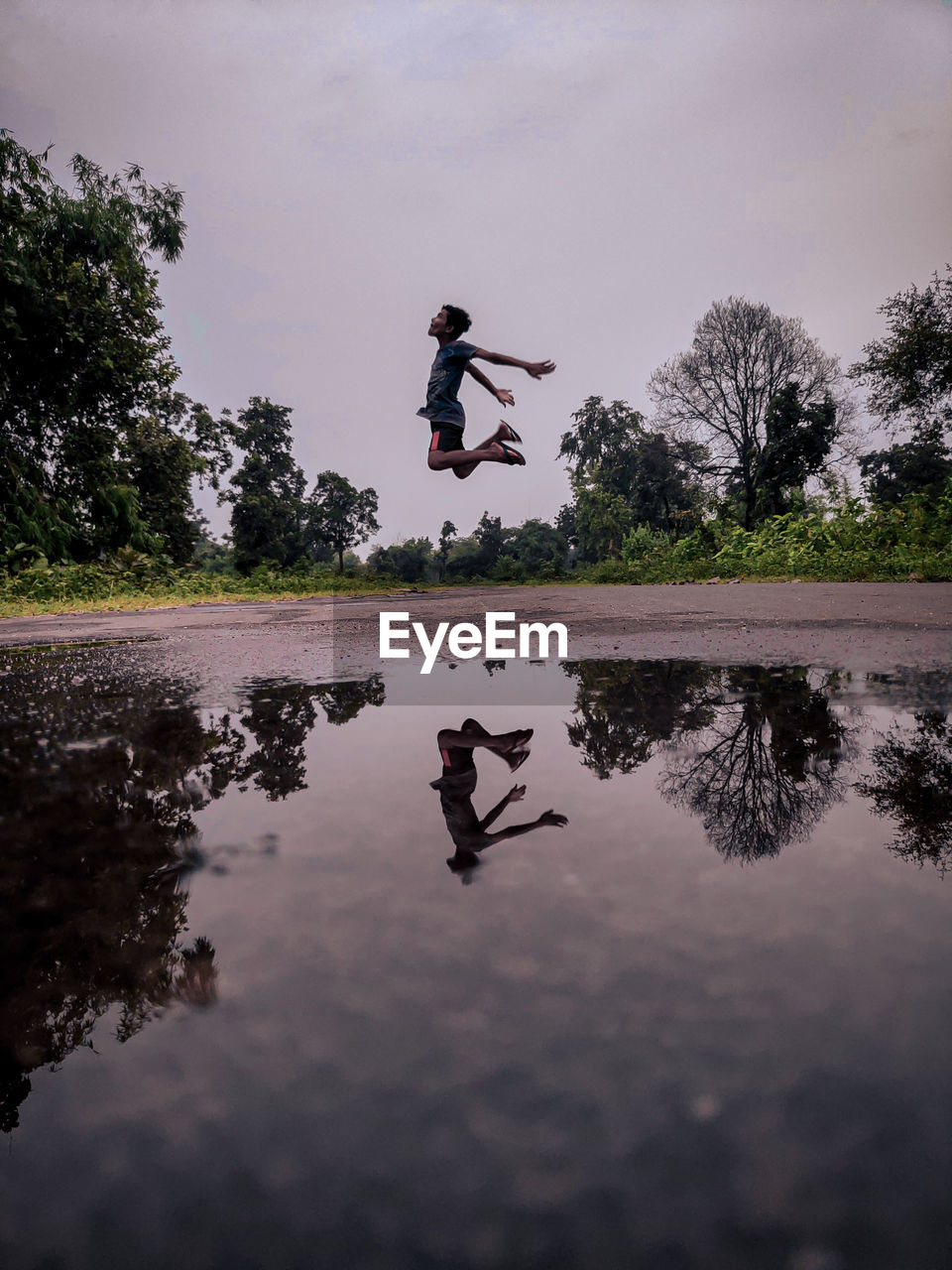 MAN JUMPING ON LAKE AGAINST SKY