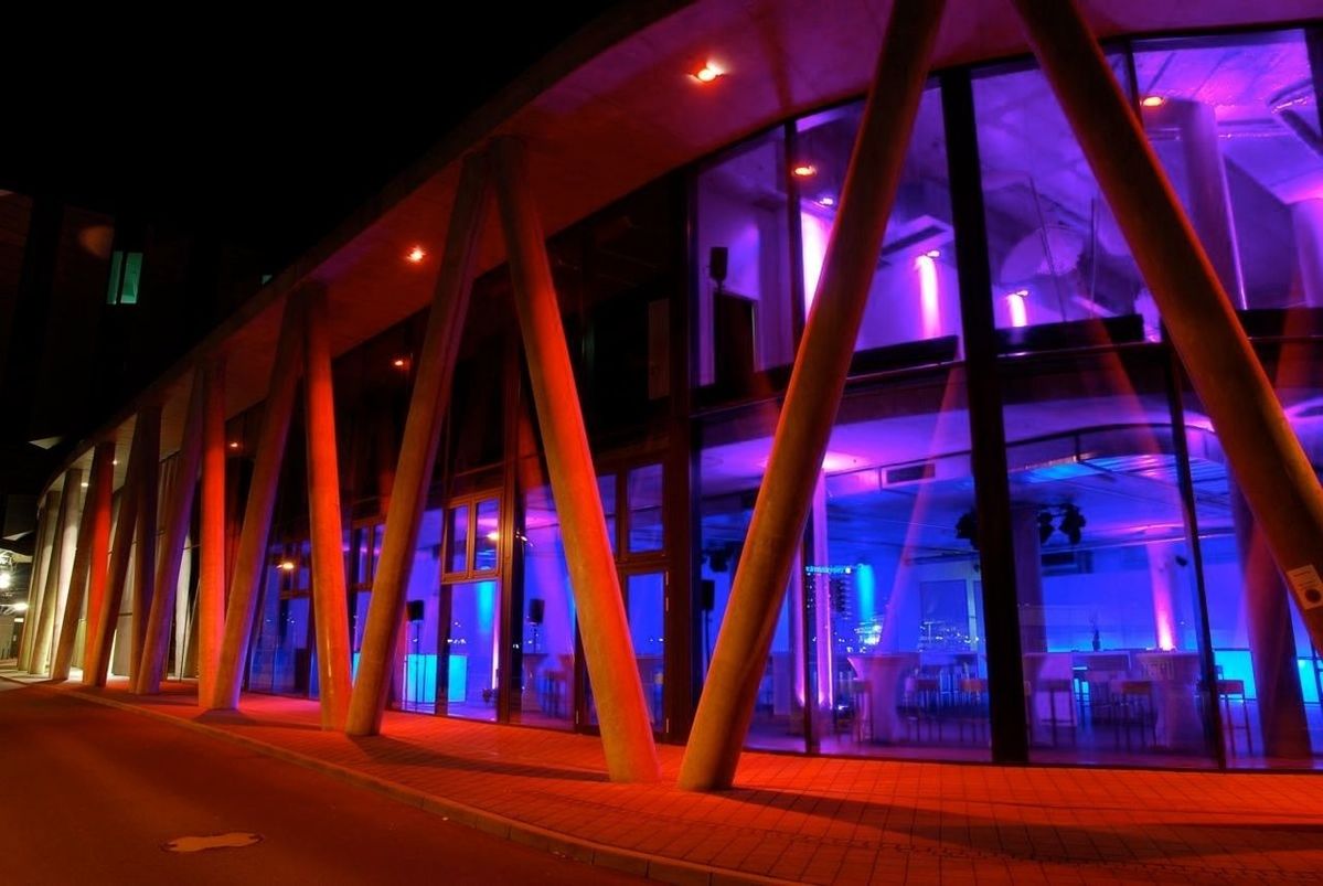 Illuminated walkway by buildings during night
