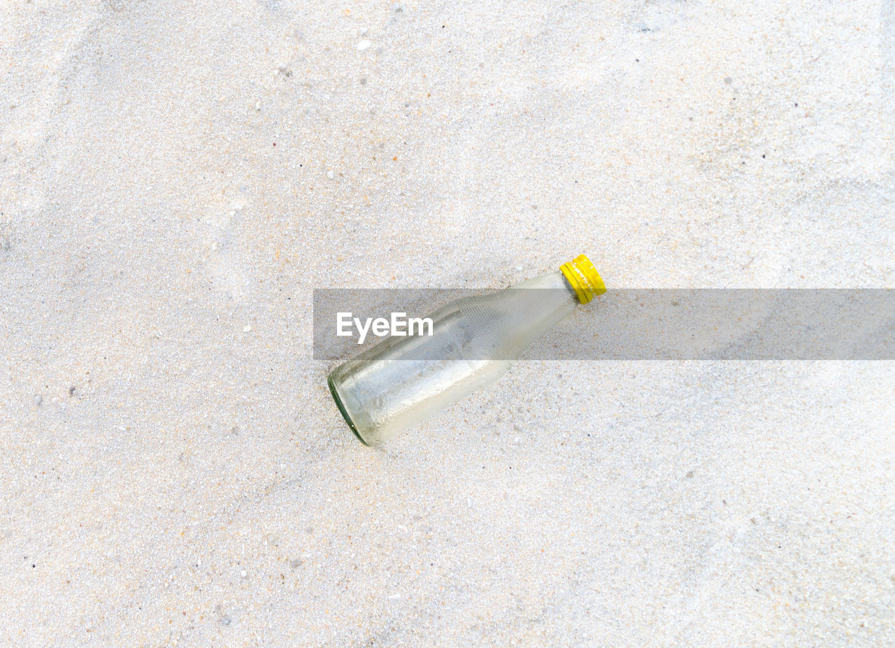 HIGH ANGLE VIEW OF CIGARETTE IN BOTTLE AGAINST GRAY BACKGROUND