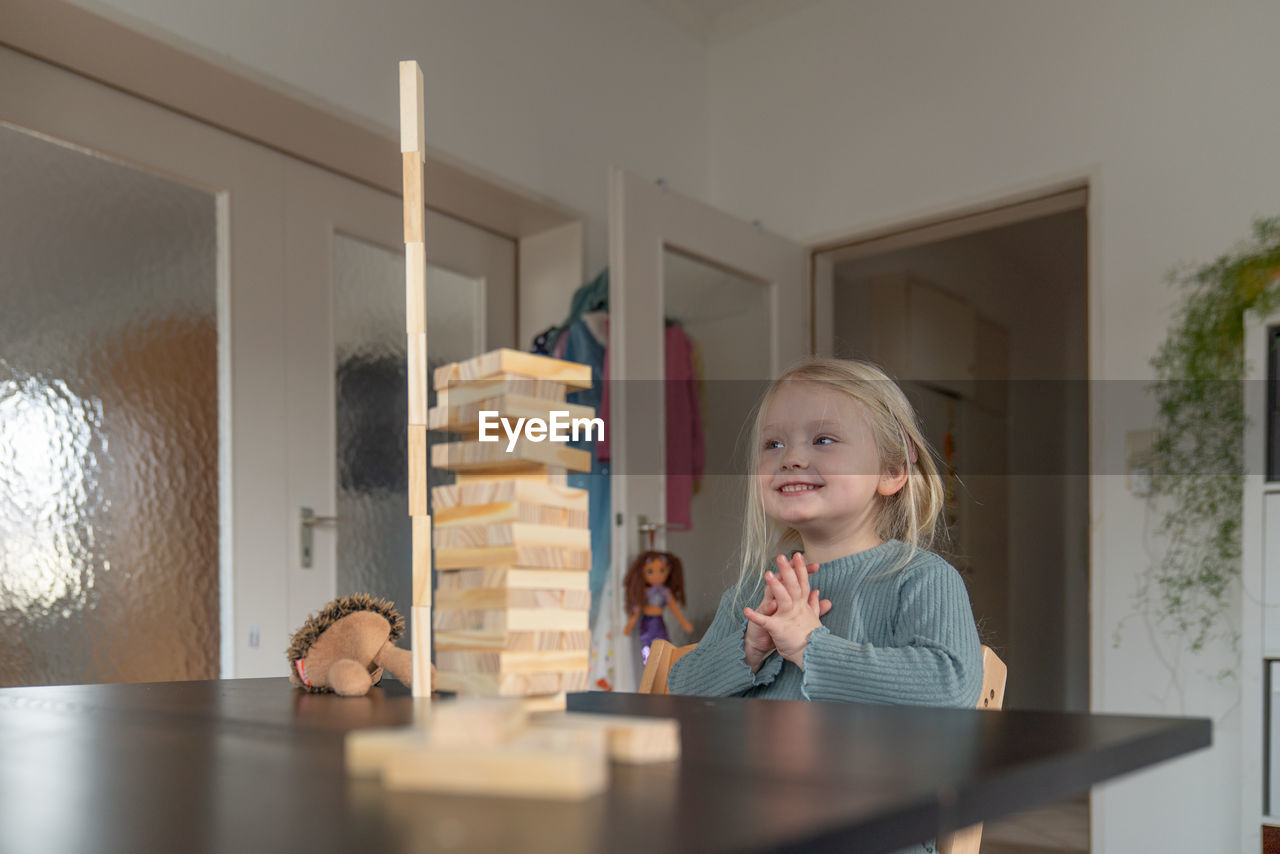 Toddler girl is looking excited on a wooden tower