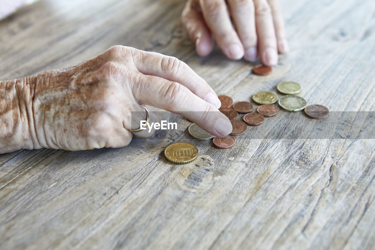 cropped hand of man holding coins on table