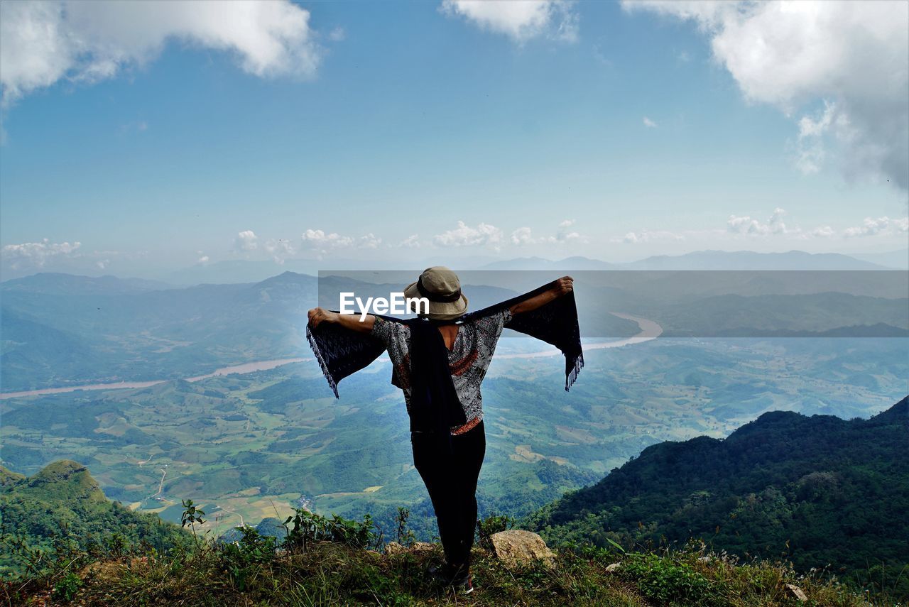 Rear view of woman with arms outstretched standing on mountain