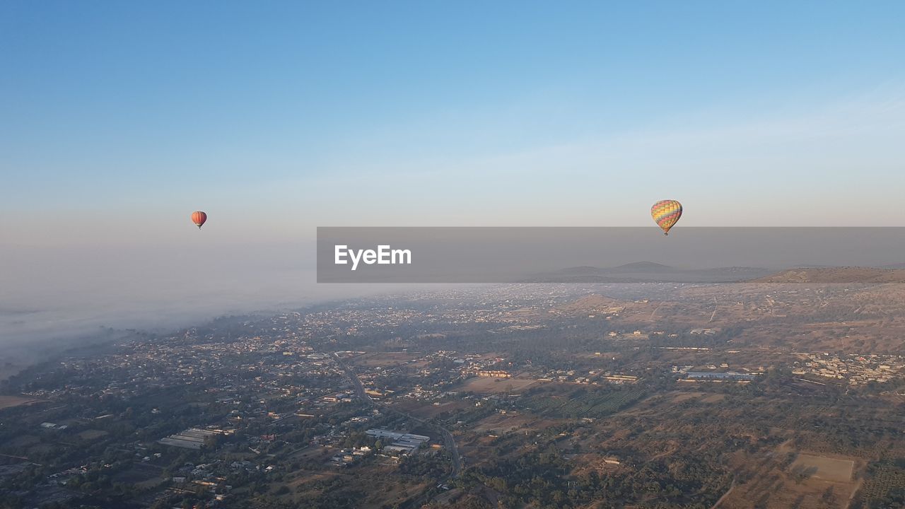 Hot air balloons flying in city against sky