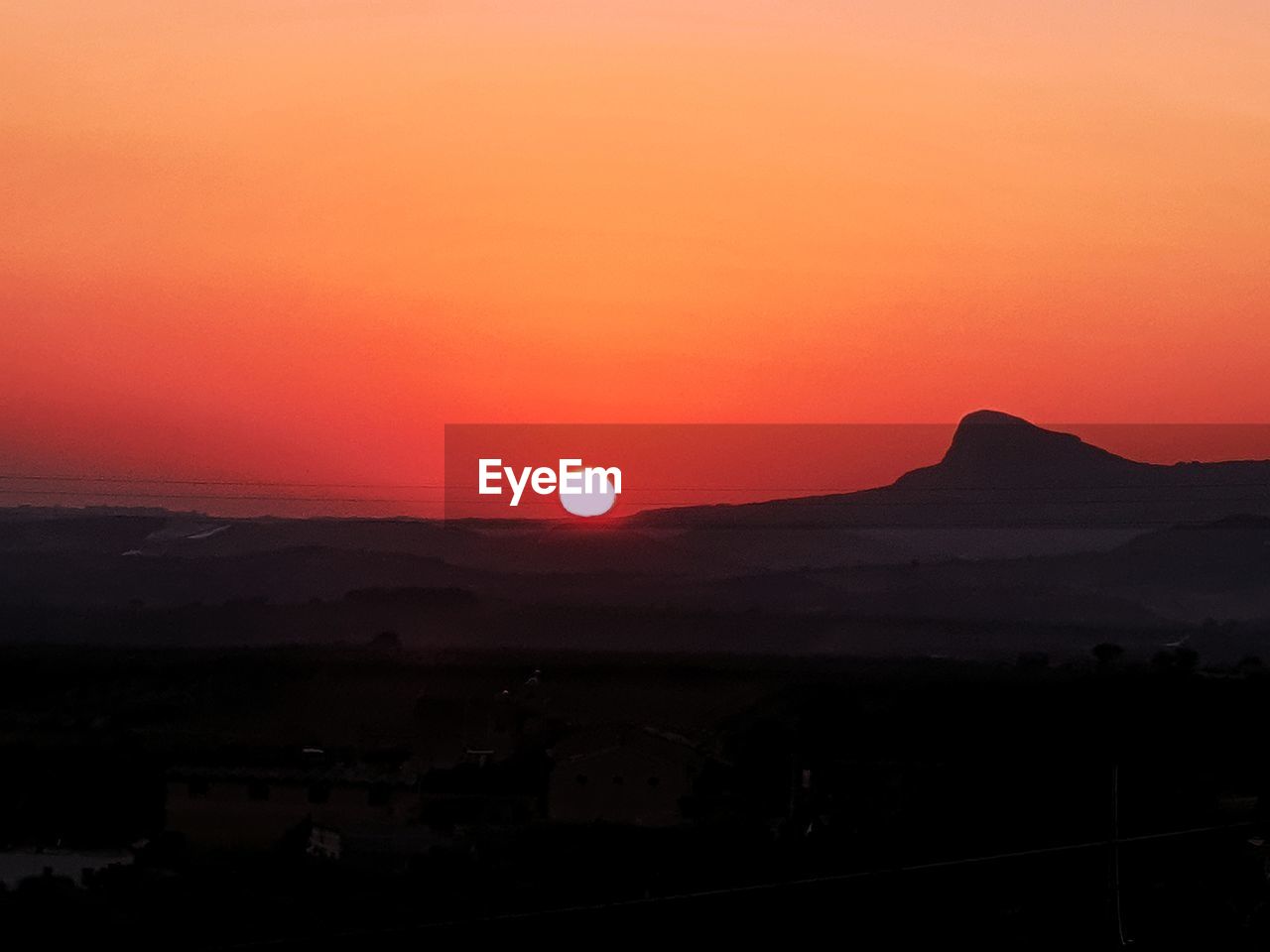 SCENIC VIEW OF SILHOUETTE MOUNTAIN AGAINST ORANGE SKY