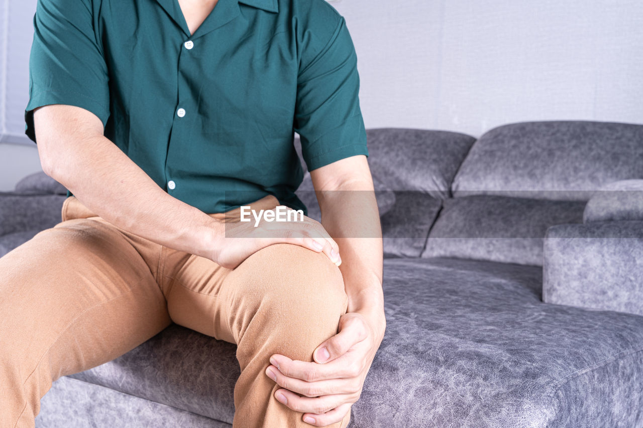Midsection of man suffering from knee pain
