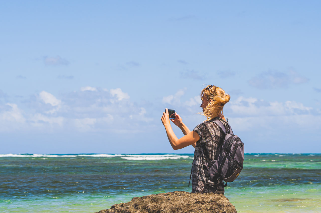 rear view of woman standing at beach against clear sky