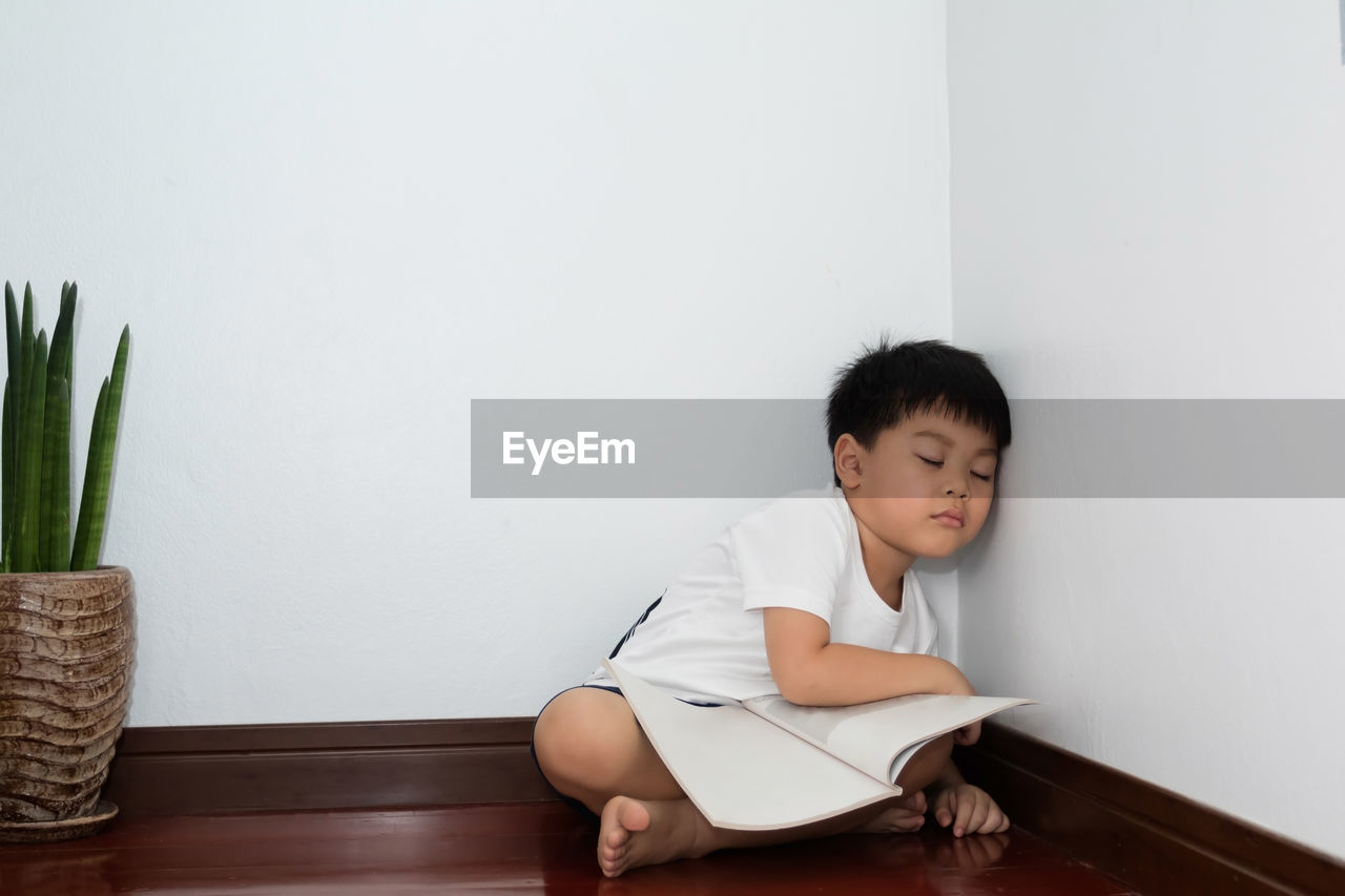 BOY LOOKING AWAY WHILE SITTING ON WALL