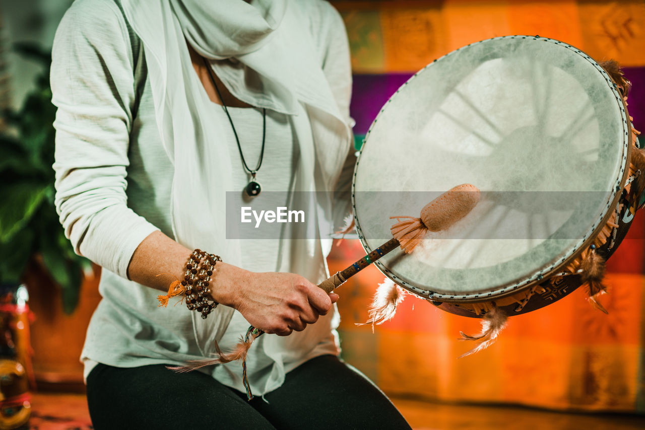 Midsection of therapist playing drum while performing music therapy at spa