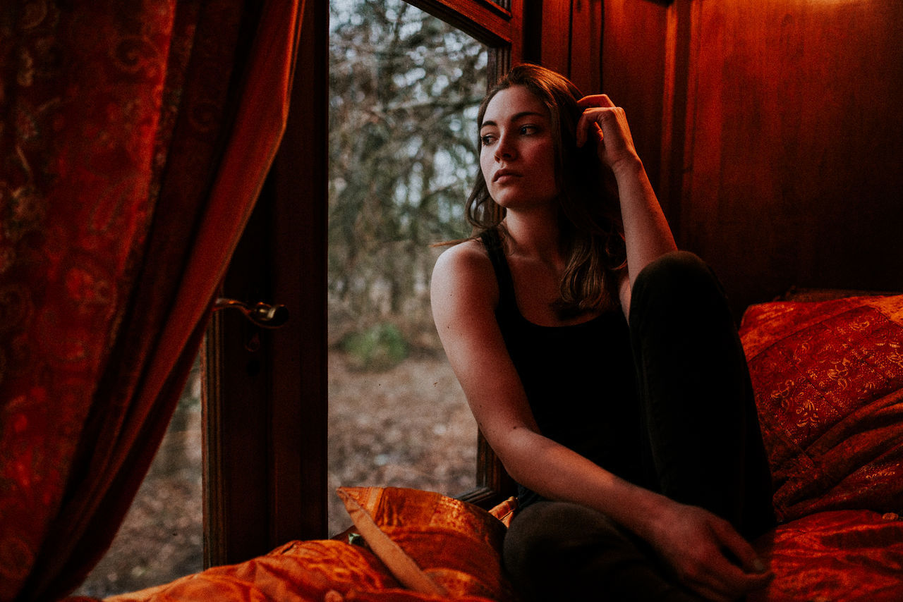 Close-up of thoughtful woman sitting by window at home