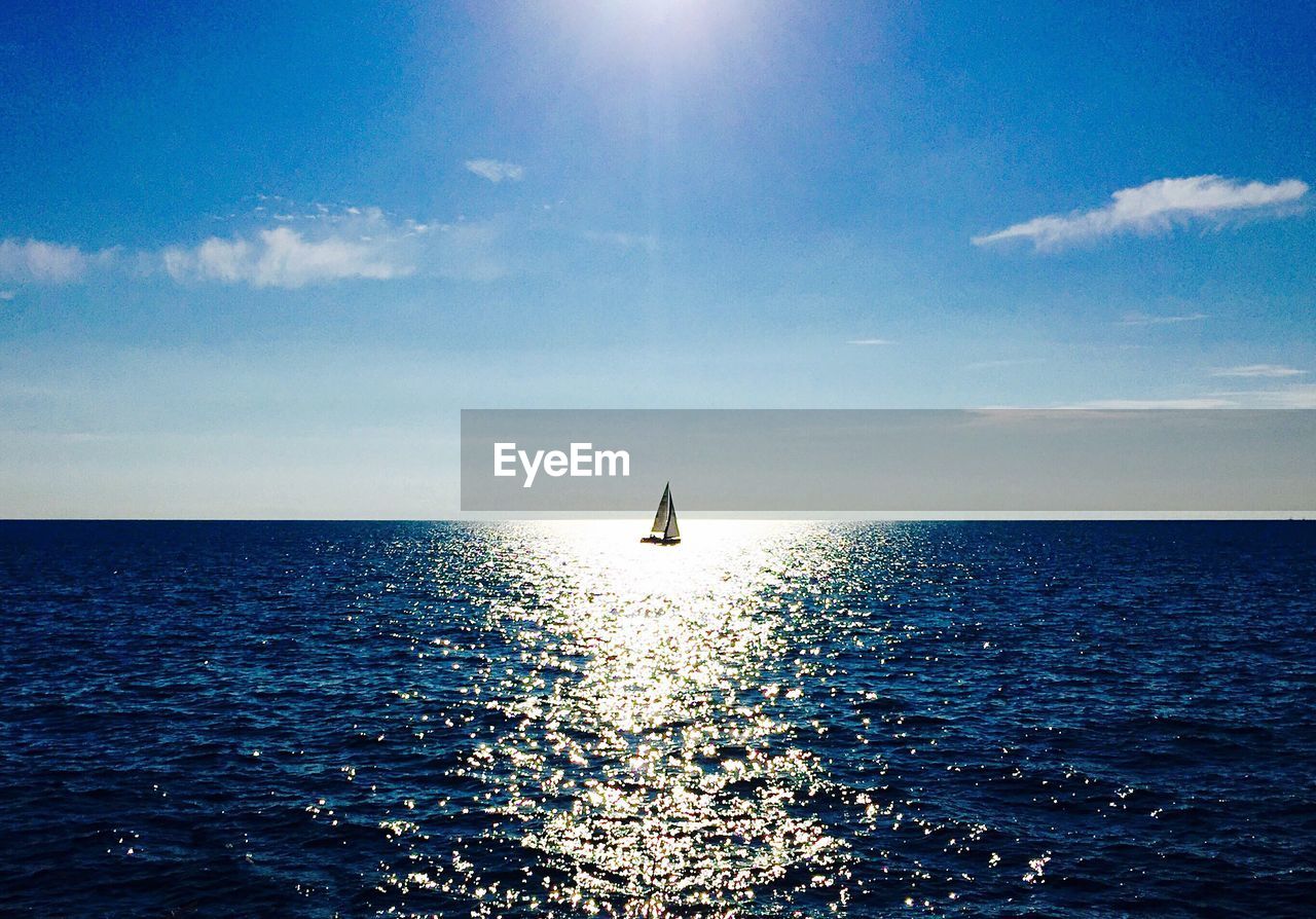 Scenic view of sea against sky with a sailing boat in the center 