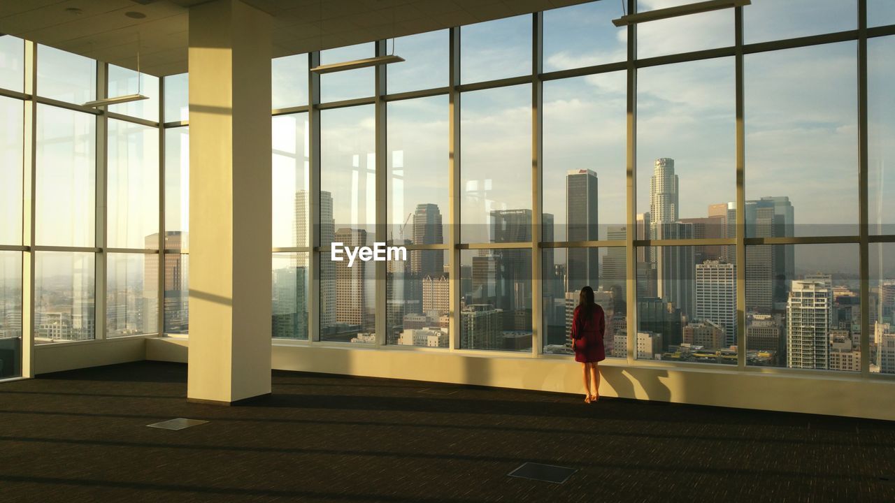 Full length rear view of woman looking at cityscape