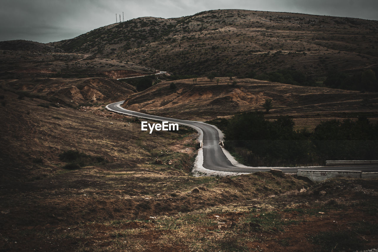 Scenic view of road by mountain against sky