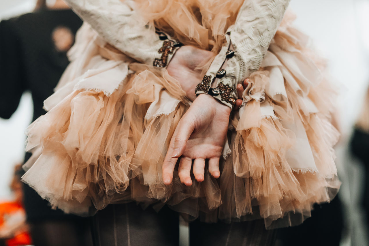 Women's hands on the background of a lush beige organza skirt