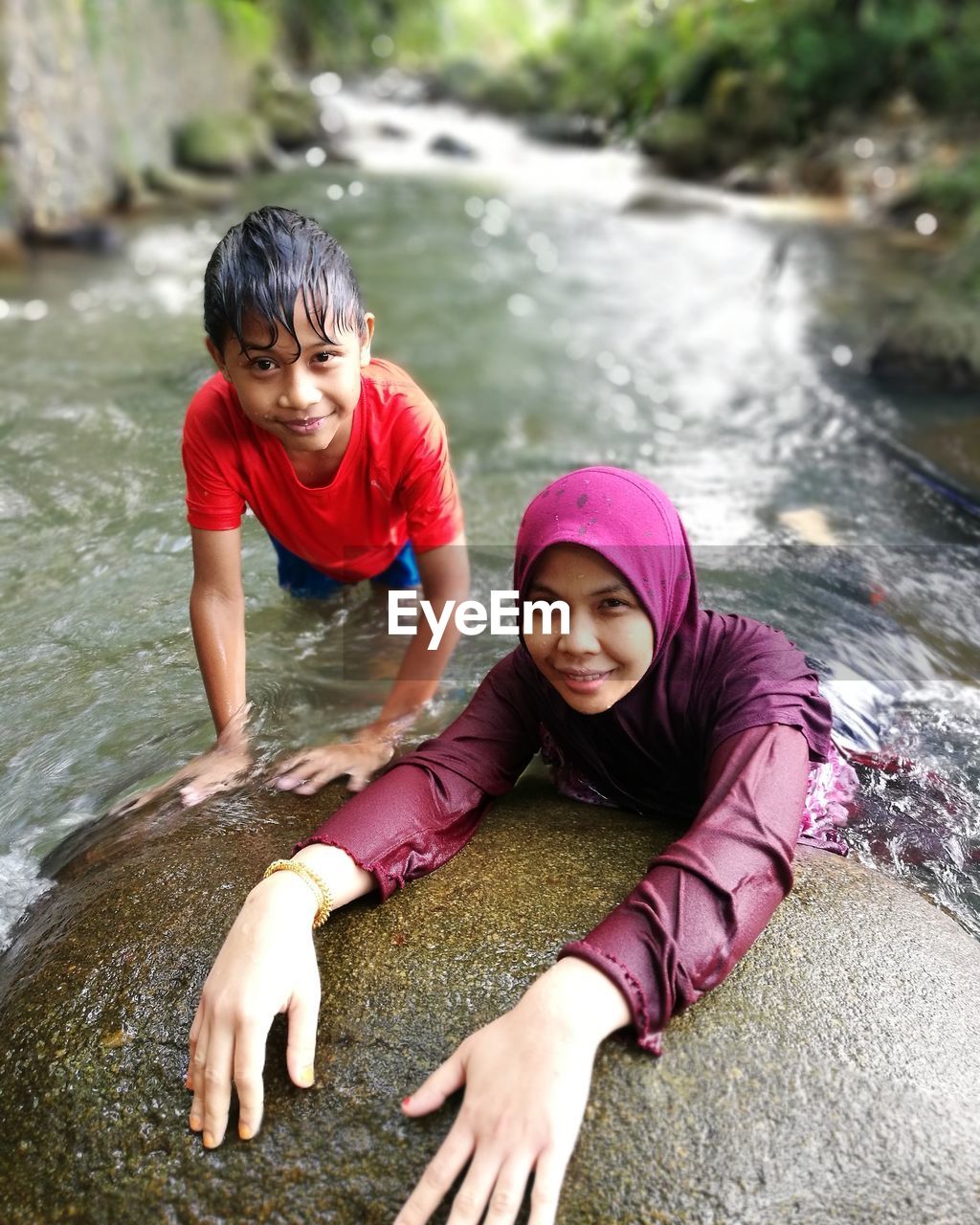Portrait of smiling mother and son enjoying in river 