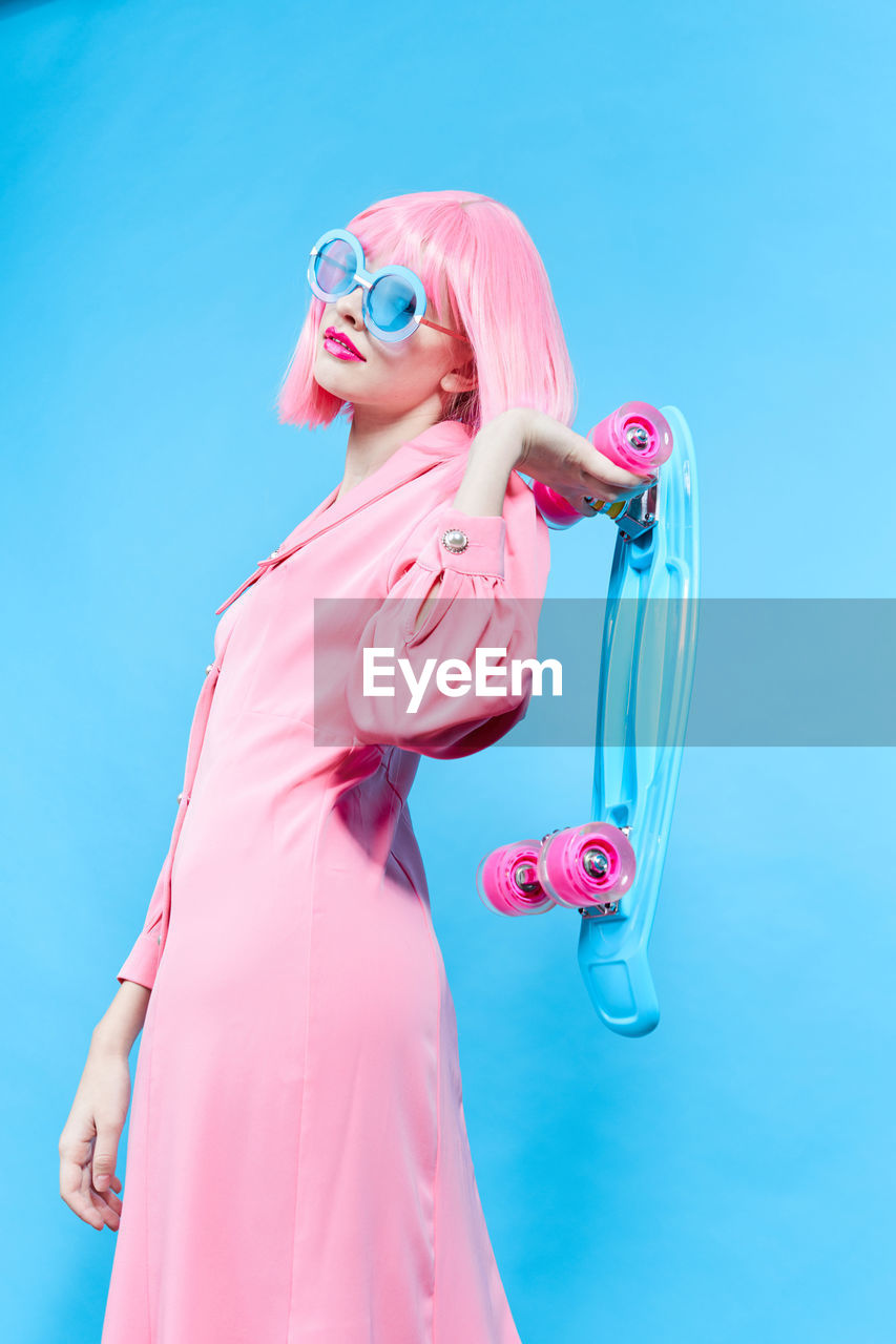 Low angle view of young woman standing against blue background