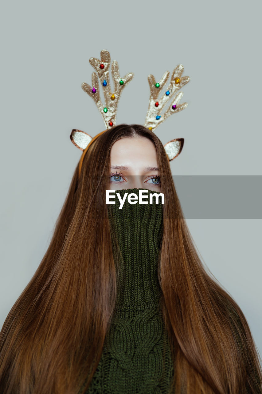 Surreal christmas portrait of a girl in a green sweater and antlers