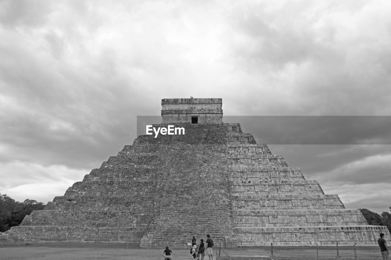 People in front of historical building against cloudy sky
