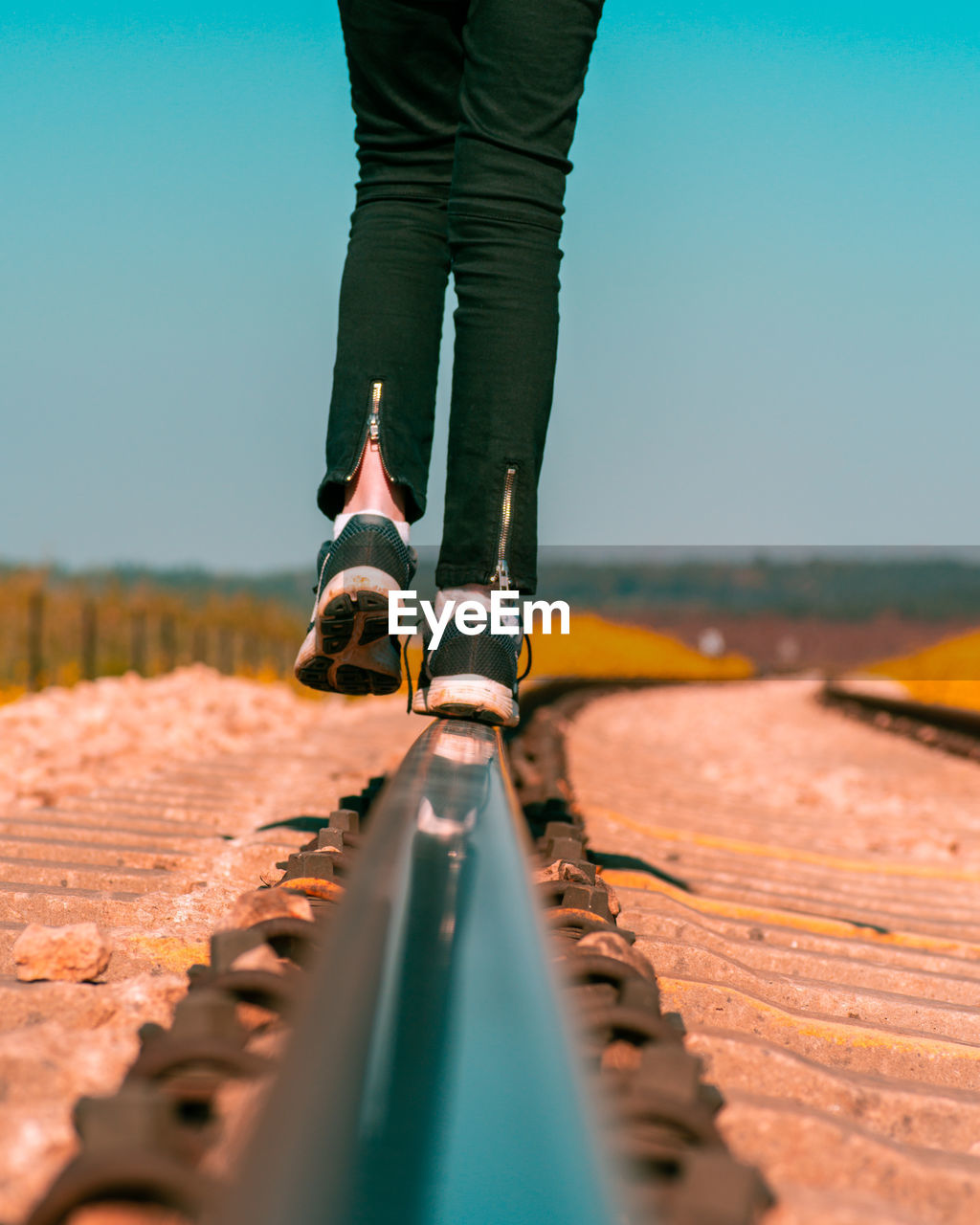 Low section of woman standing on railroad track