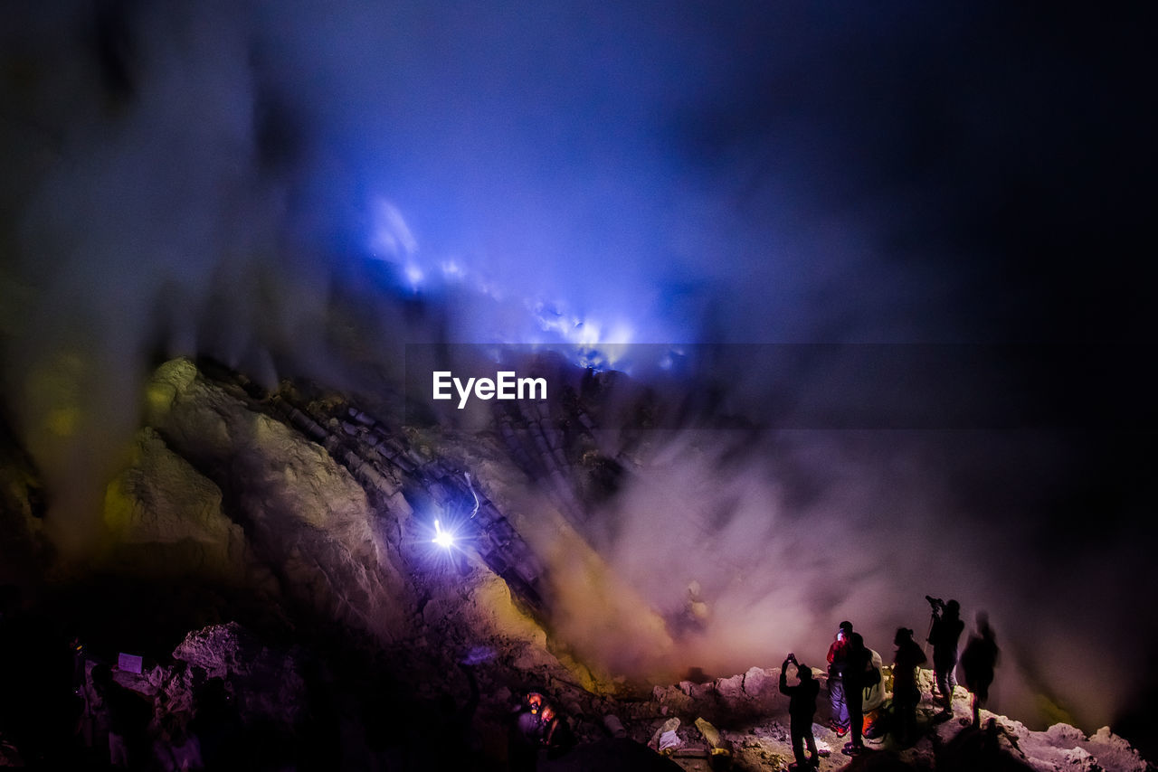 People on standing on mountain against sky at night