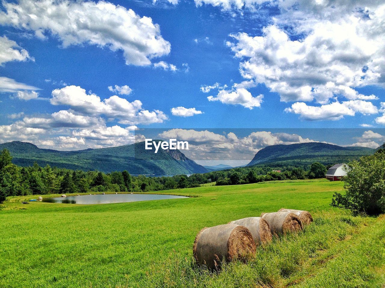 Hay bales on grassy field against sky
