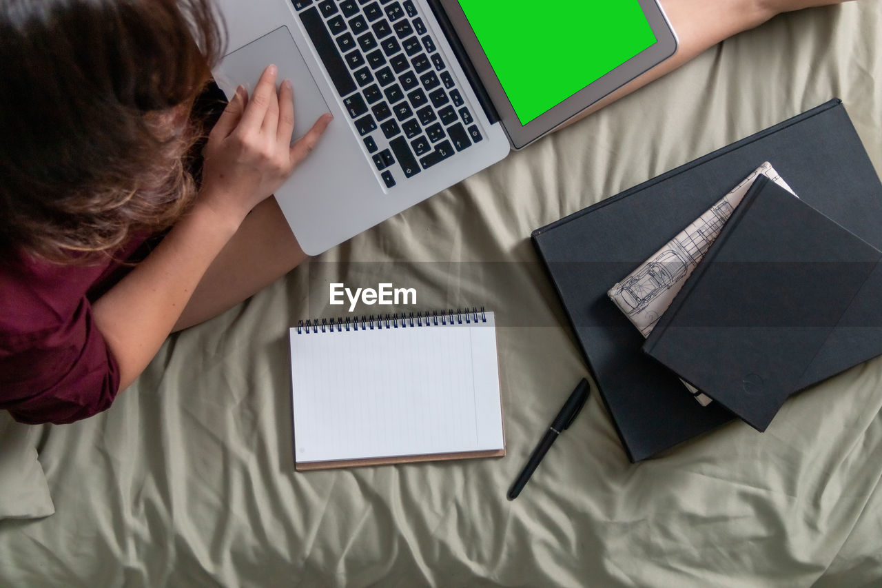High angle view of woman using laptop while sitting on bed at home